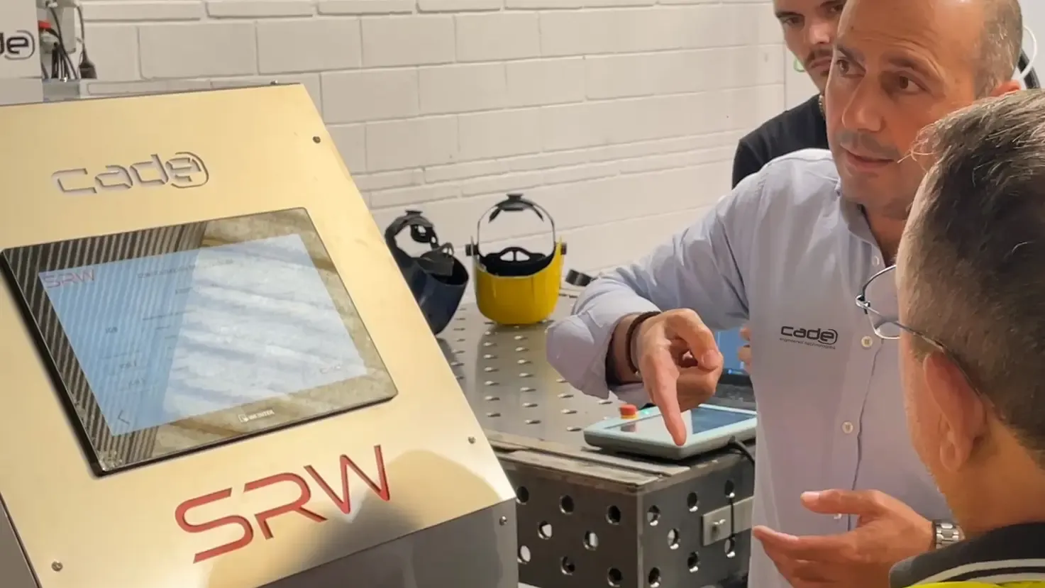 Técnico de CADE mostrando en una tableta el funcionamiento del equipo SRW a un grupo de visitantes